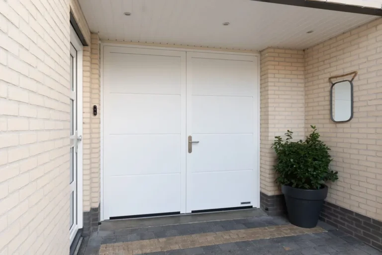 Witte openslaande Hormann garagedeuren onder een overkapping