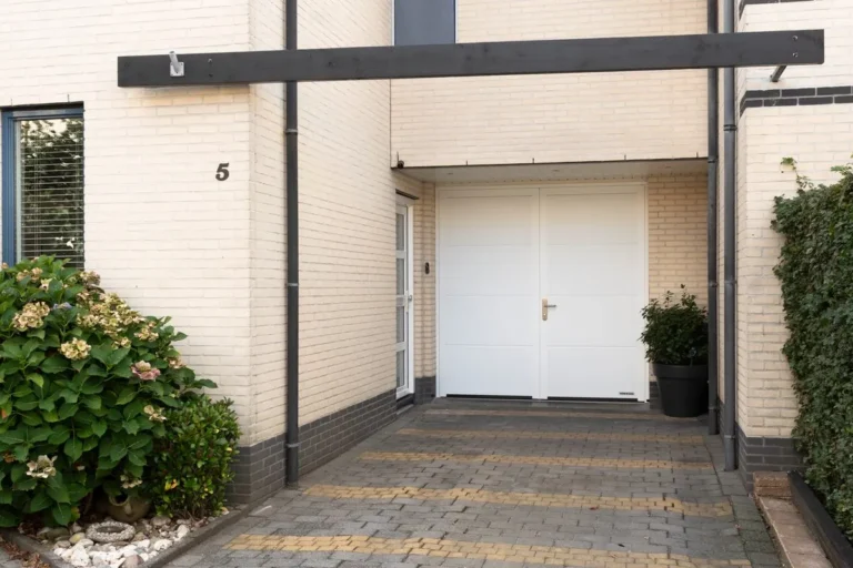 Witte openslaande Hormann garagedeuren aan het einde van een oprit