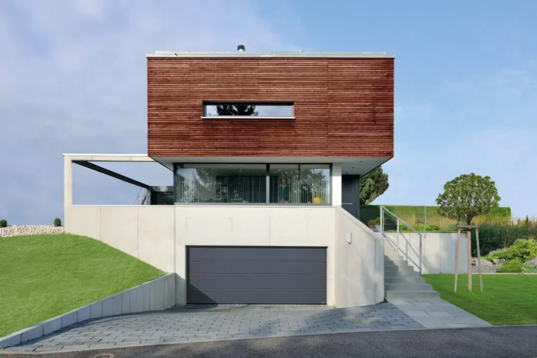 Antraciete sectionaaldeur bij een moderne woning met houtgevel