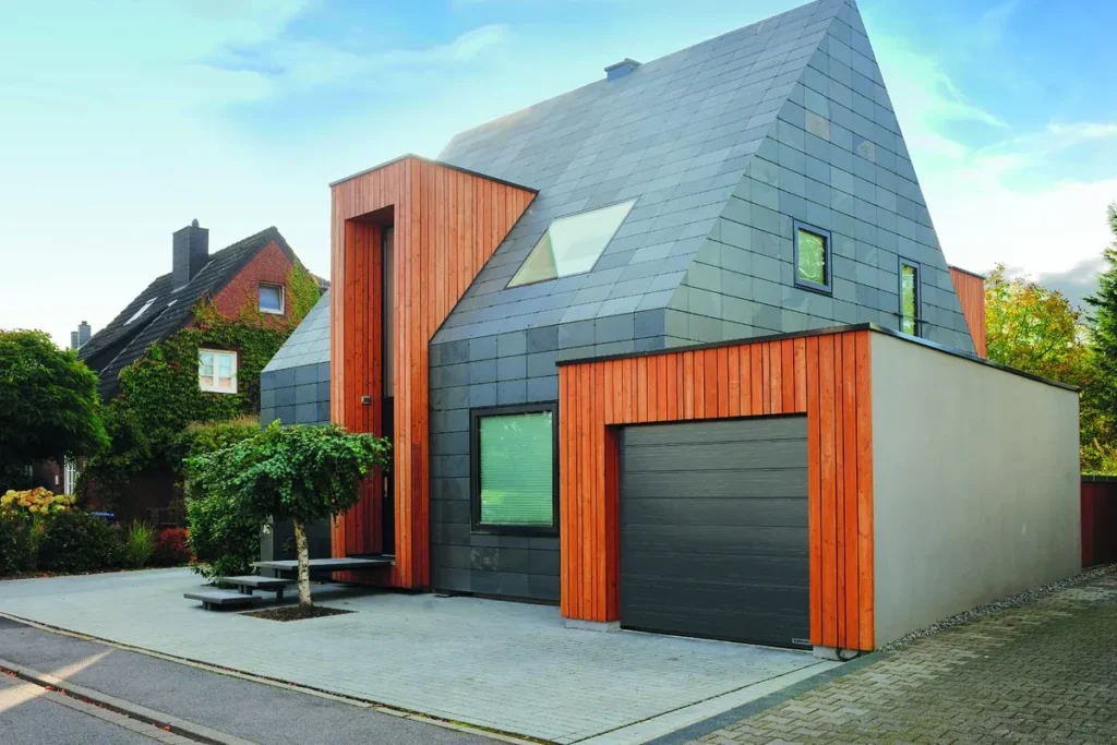 Antraciete sectionaaldeur bij een woning met leien gevel en houtaccent
